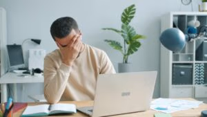 Vermoeide werknemer achter laptop